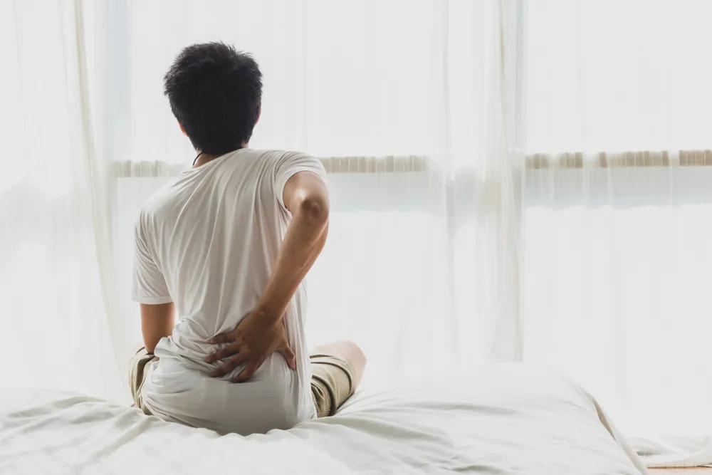 a man holding his back after experiencing back pain in bed