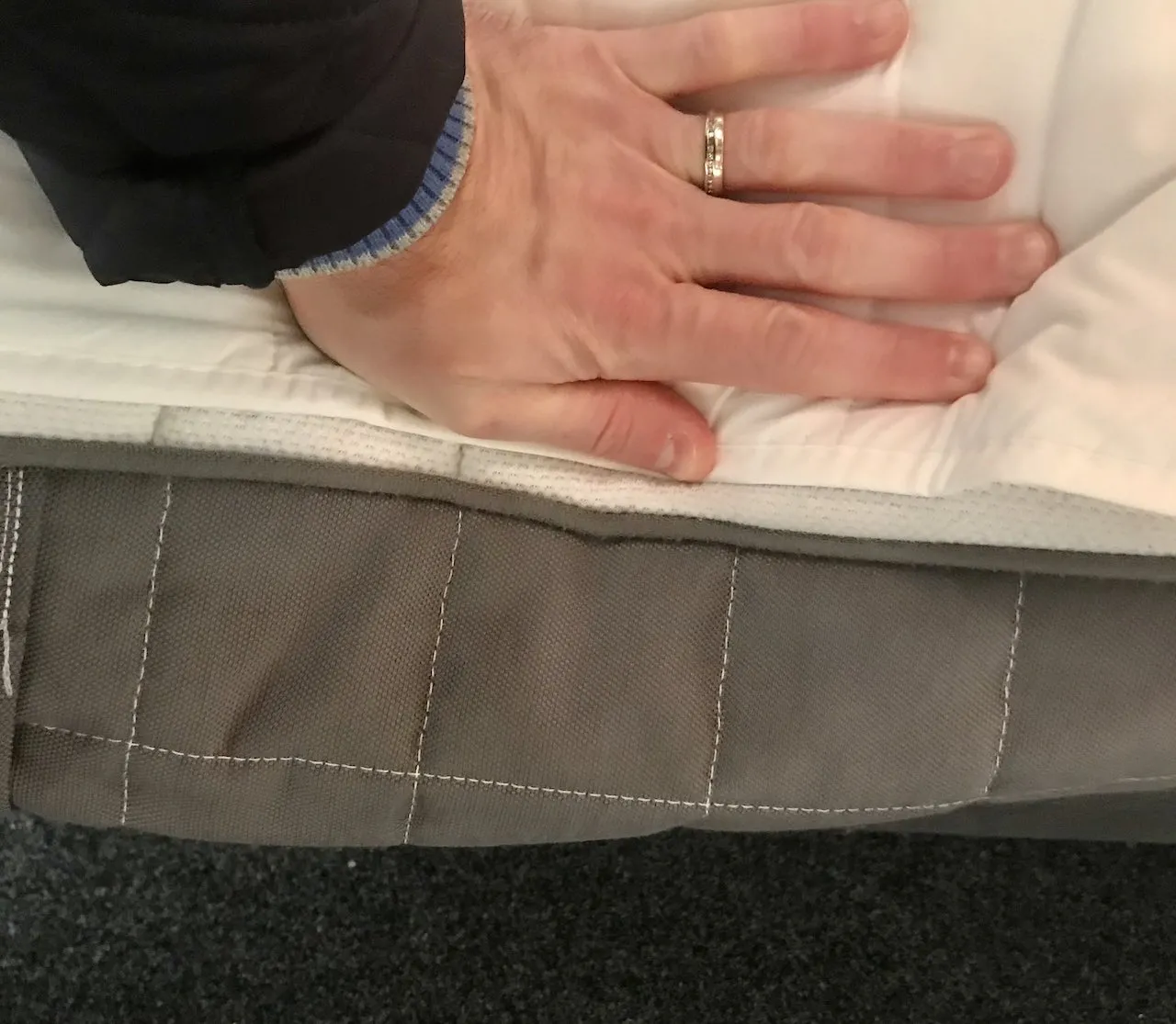 A hand pushing the side of an Ikea mattress