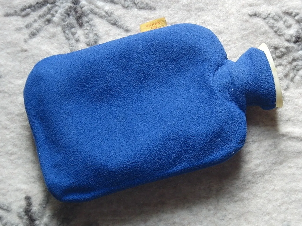 A hot water bottle with a fleecy cover