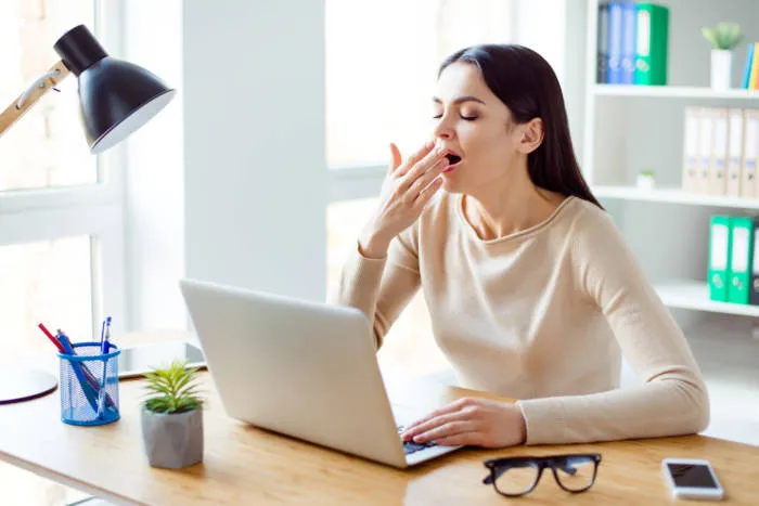 Woman yawning at a desk