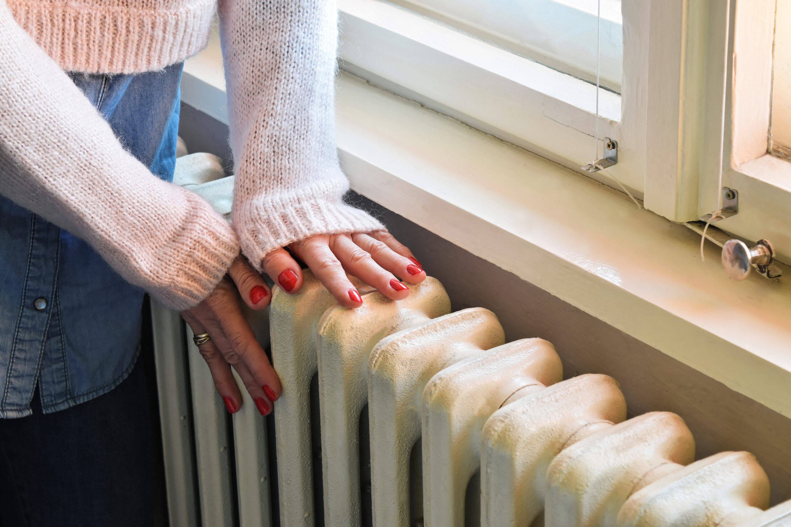 a woman with painted finger nails feeling the temperature of a radiator