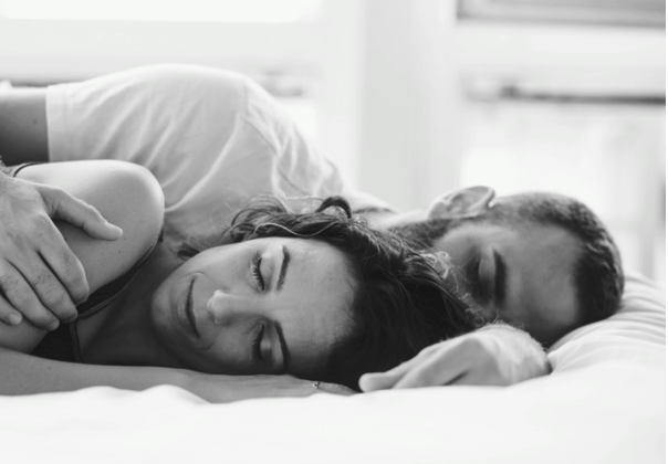 A man and woman sleeping on their sides in bed