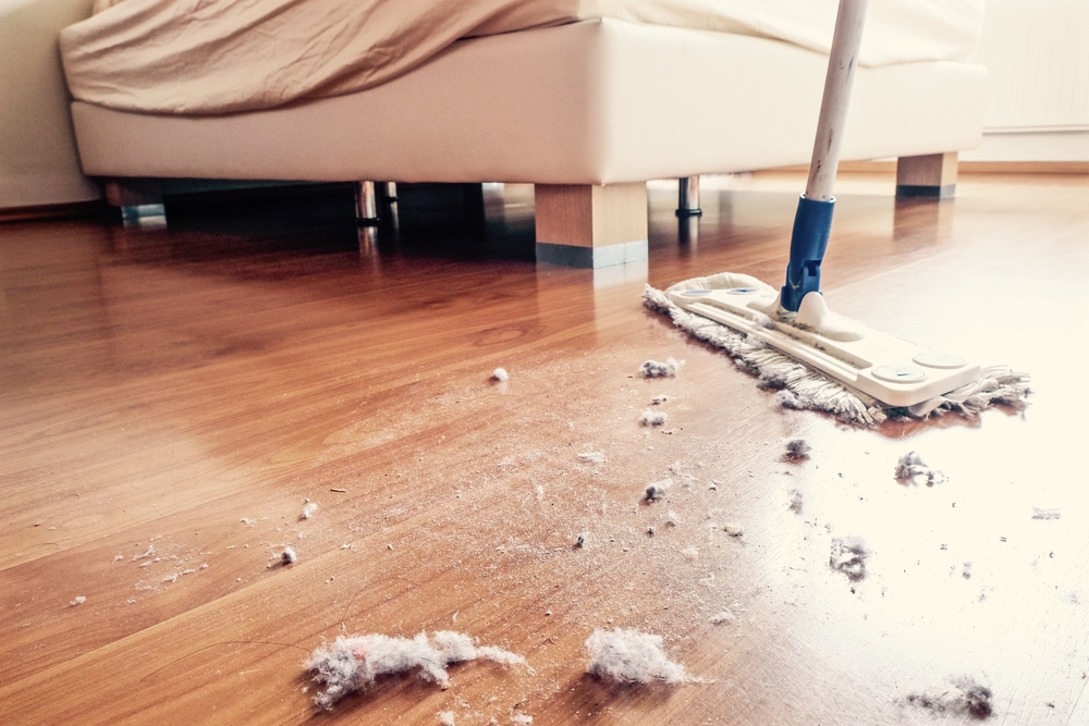A floor mop being used to dust a bedroom floor